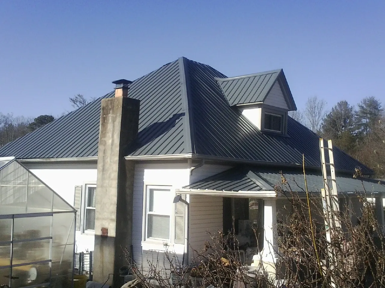 Dark blue standing seam metal roof on a white farmhouse with dormer — Slate & Tile Roof Repair by Roofing Brothers in Olema