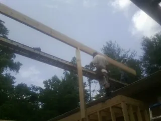 Carpenter setting a ridge beam over a new addition frame — Ice Dam Removal by Roofing Brothers in Olema