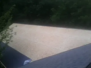 New OSB roof sheathing installed beside an existing shingle roof in Olema