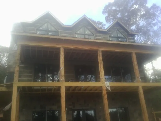 Dormers and porch framing on a large log home under construction — Roof Coating work by our crew in Olema