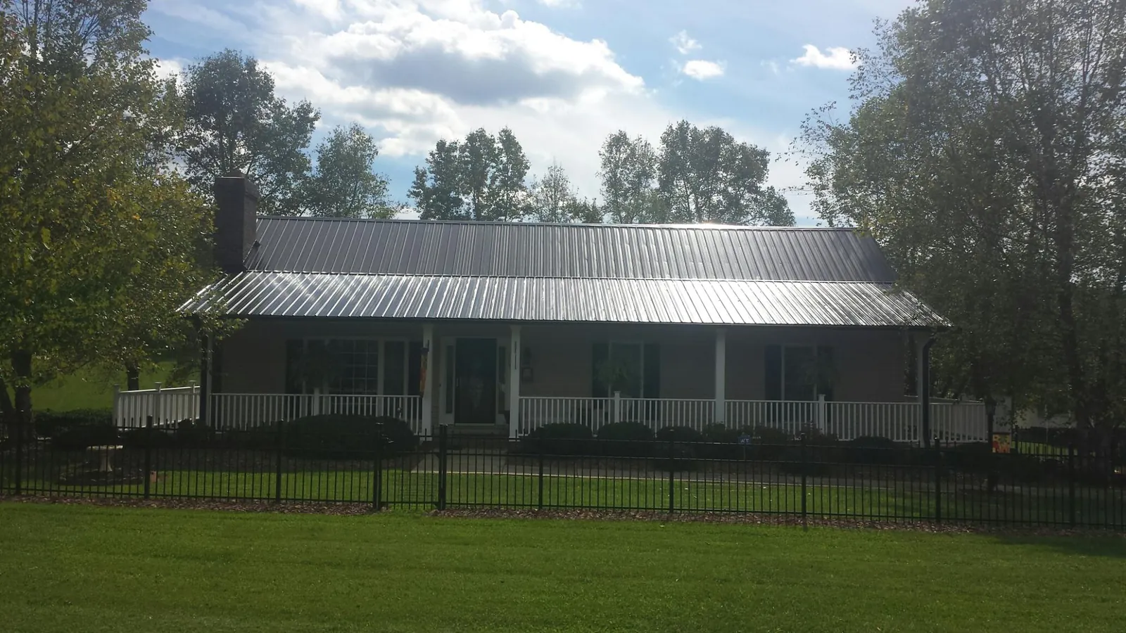 Gray metal roof on a brick ranch with a full width front porch — Gutter Guard Installation work by our crew in Olema