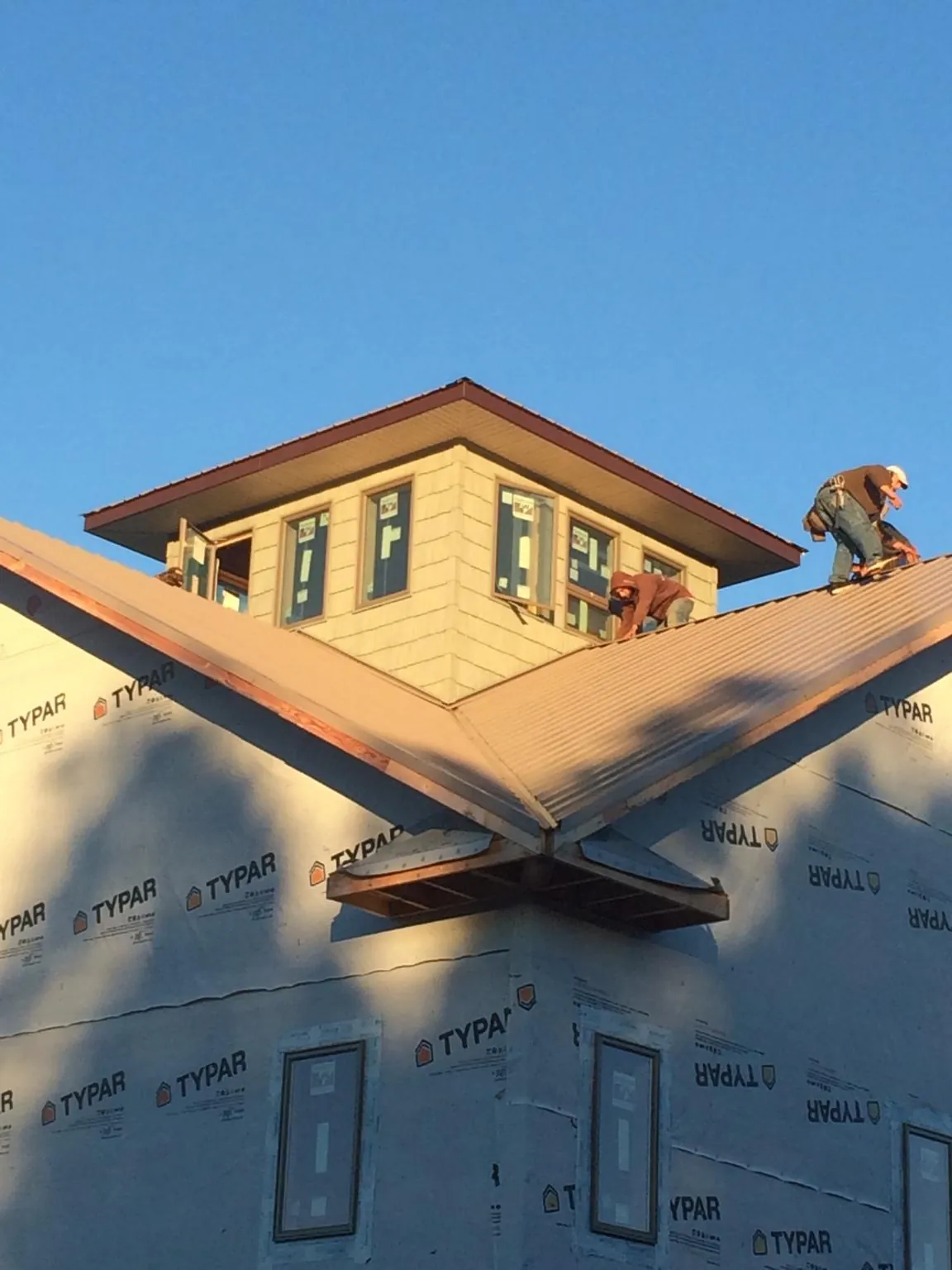 Roofers working around a rooftop cupola on a new metal roof at sunset — Roof Waterproofing in Olema by Roofing Brothers